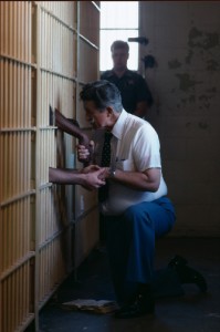 Pastor sosteniendo los brazos de dos encarcelados